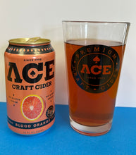 Load image into Gallery viewer, A 12 fl oz can of Ace Craft Cider Blood Orange next to a clear pint glass filled with amber-brown cider, both featuring the Ace brand logo, set on a blue surface against a white background.